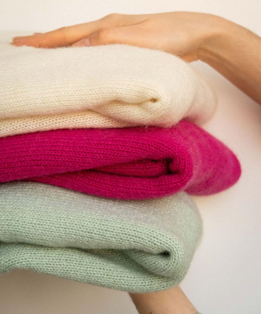 Une femme tenant entre les mains une pile de pulls