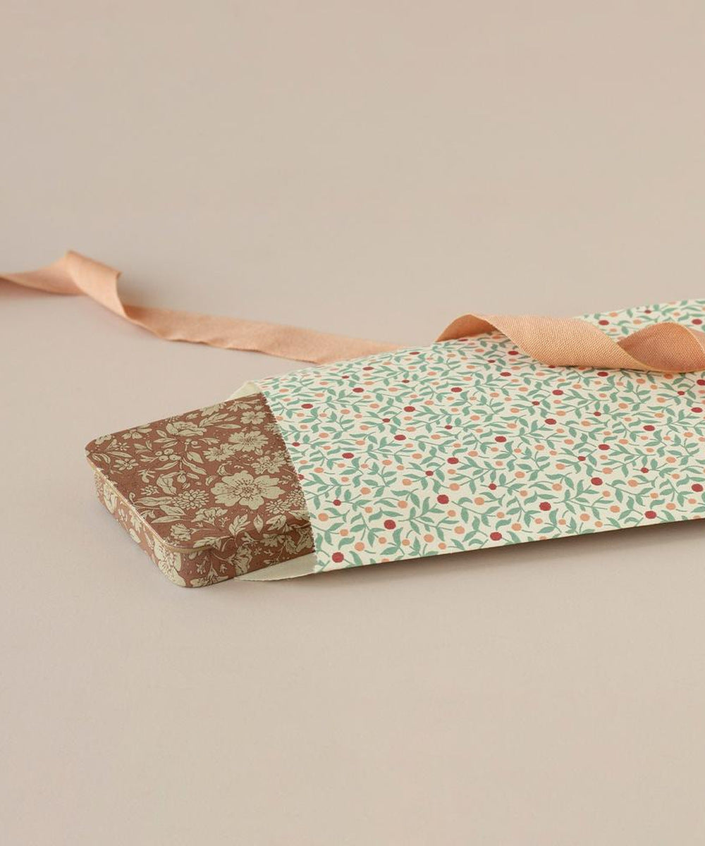 Boîte Blossom ocre Maileg glissée dans un paquet cadeau fleuri