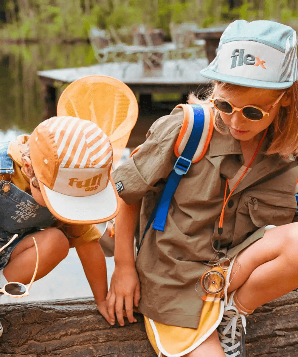 Deux enfants portant des casquettes Ki ET LA au bord d'un lac, ambiance aventure nature