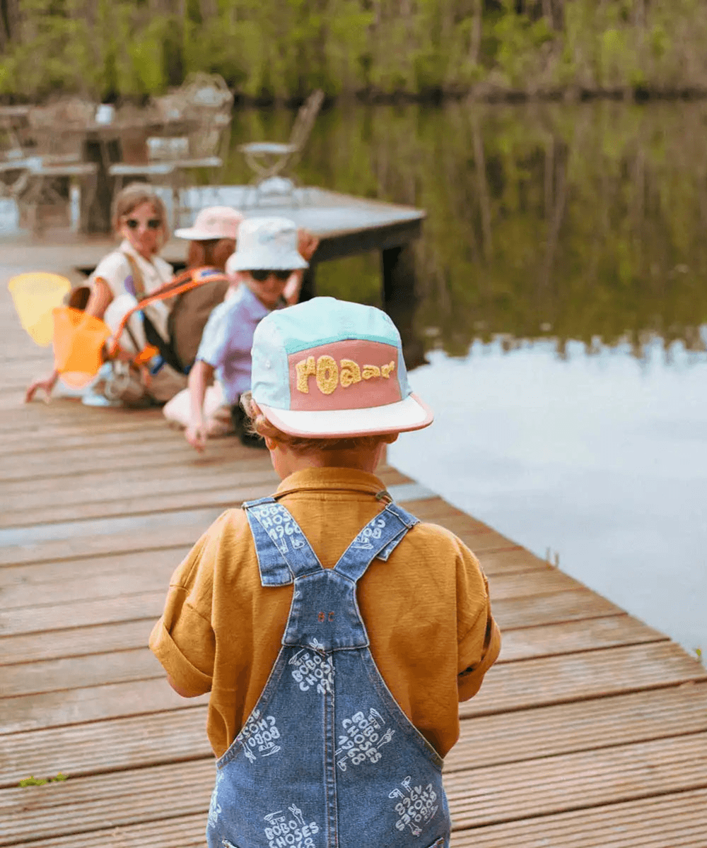 Enfant portant à l'envers, la casquette Roar Ki ET LA  au bord d'un lac, ambiance aventure nature