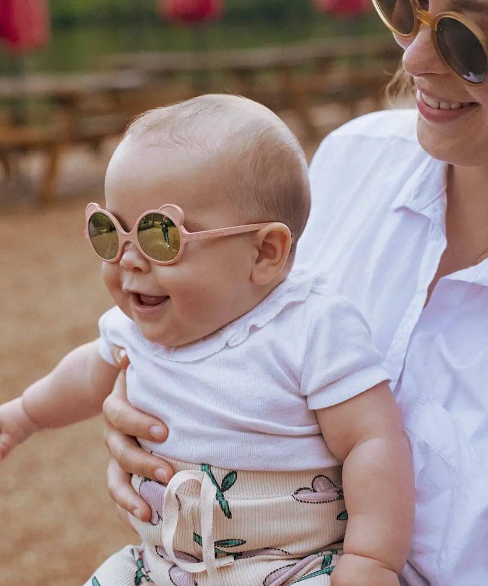 Lunettes Ourson Couleur Rose Pêche de la marque KI ET LA portées par un bébé dans les bras de sa mère