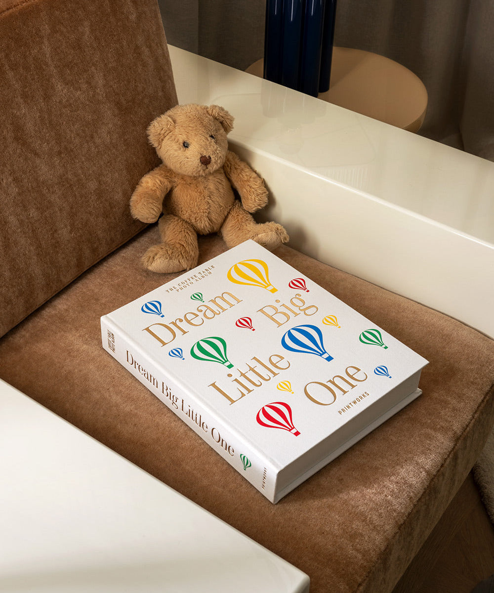 Album Dream Big Little One posé près d’un ours en peluche dans une chambre de bébé