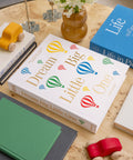 Album photo Printworks Dream Big Little One sur une table avec des jouets
