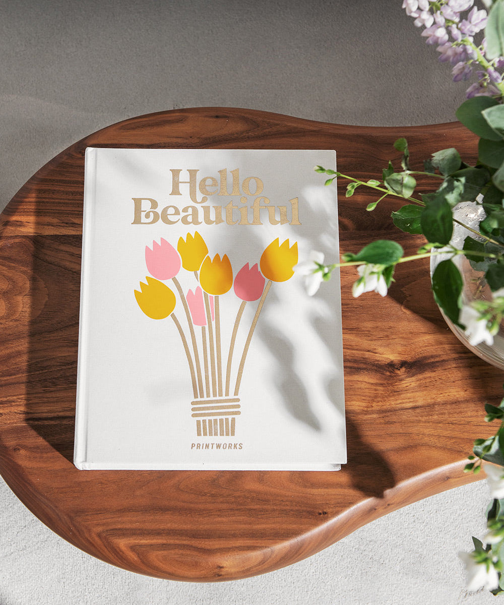 Album photo Hello Beautiful Printworks posé sur une table en bois avec des fleurs