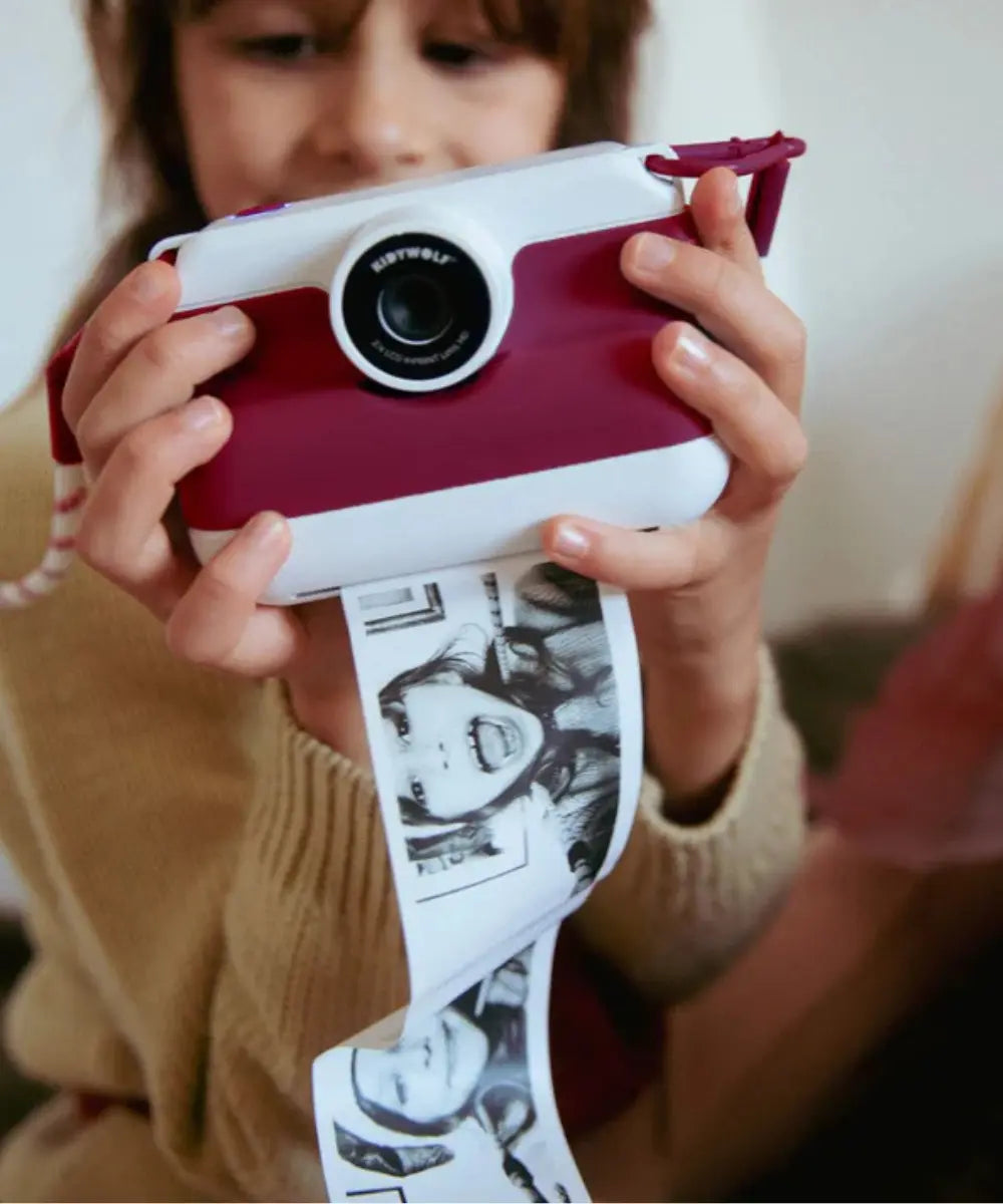 Enfant en train d'utiliser l'Appareil photo instantané pour enfant K-Print rouge de Kidywolf avec écran couleur arrière et fente d'impression.