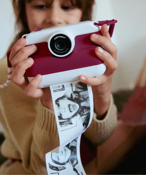Enfant en train d'utiliser l'Appareil photo instantané pour enfant K-Print rouge de Kidywolf avec écran couleur arrière et fente d'impression.