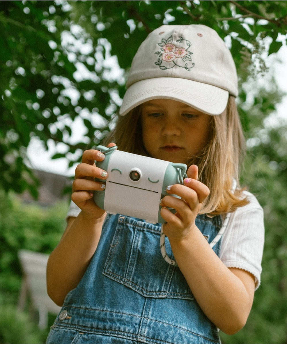 Enfant tenant un Kidyprint vert pendant l’impression d’une photo