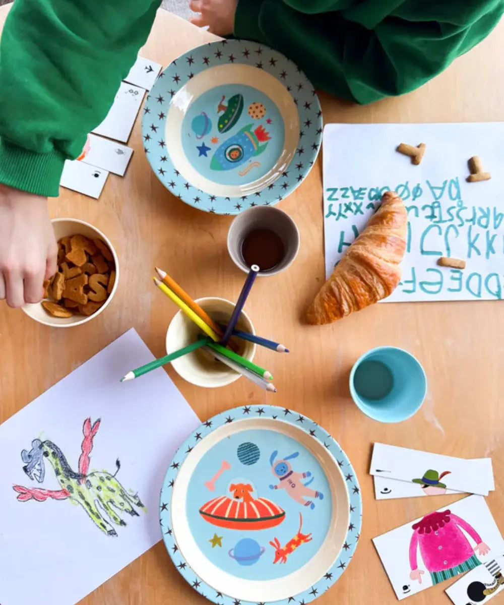 Assiette creuse en mélamine Dogs in Space de la marque danoise Rice pendant le goûter d'un enfant