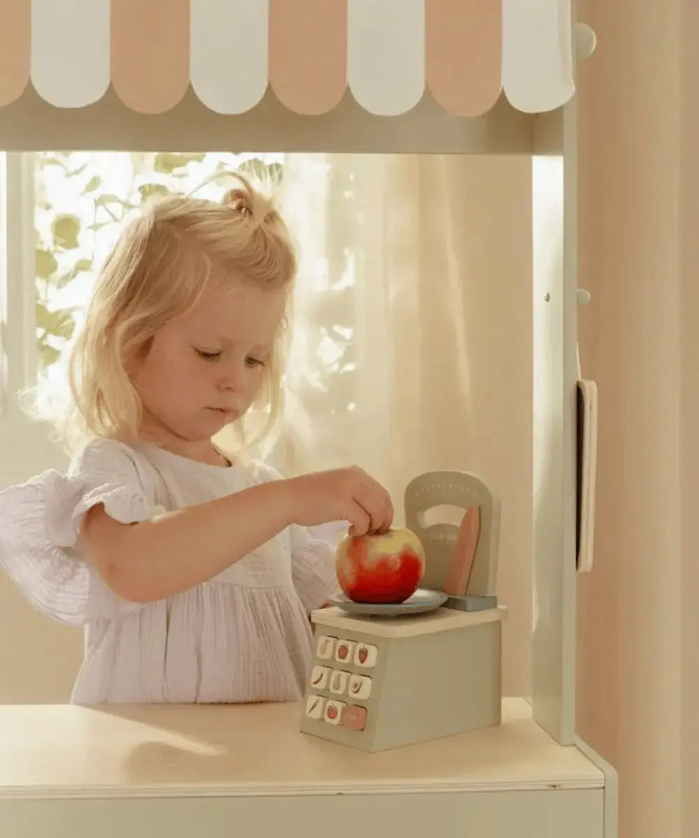 Enfant de 3 ans en train de peser une pomme avec la balance en bois Little Dutch