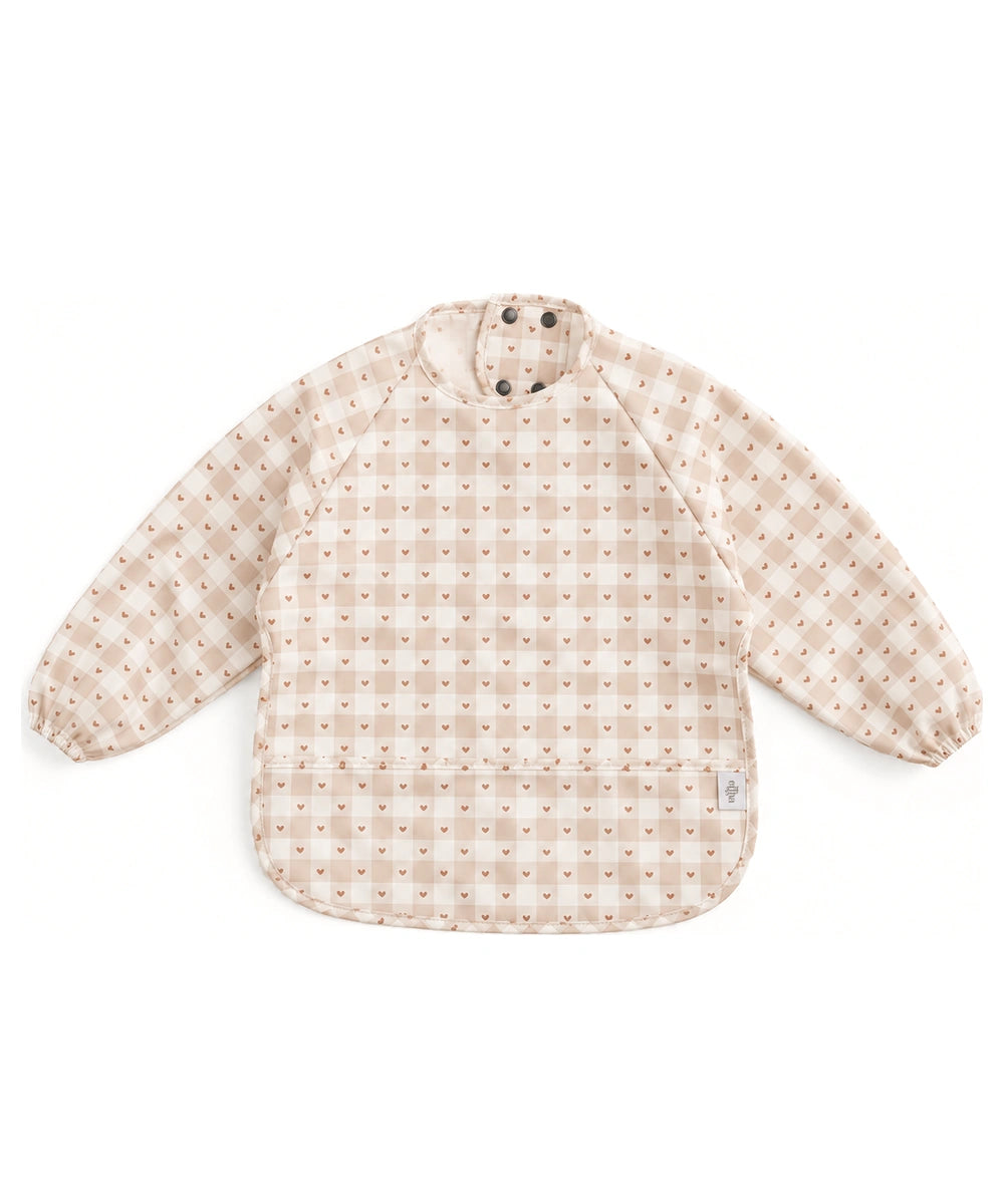 Bavoir tablier à manches longues Jolis carreaux de Mrs Ertha, à carreaux crème et beige et petits cœurs, sur fond blanc