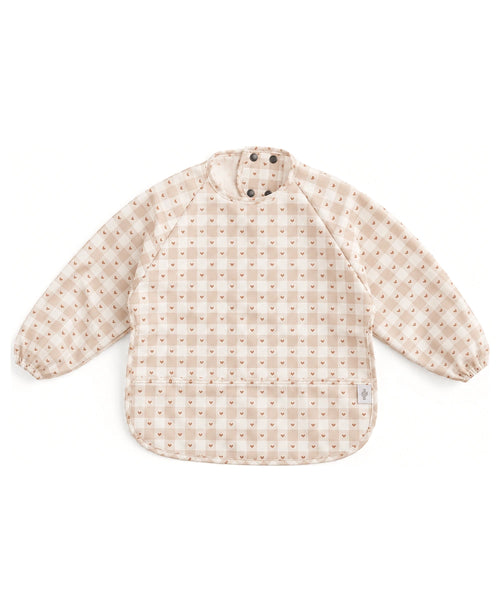 Bavoir tablier à manches longues Jolis carreaux de Mrs Ertha, à carreaux crème et beige et petits cœurs, sur fond blanc