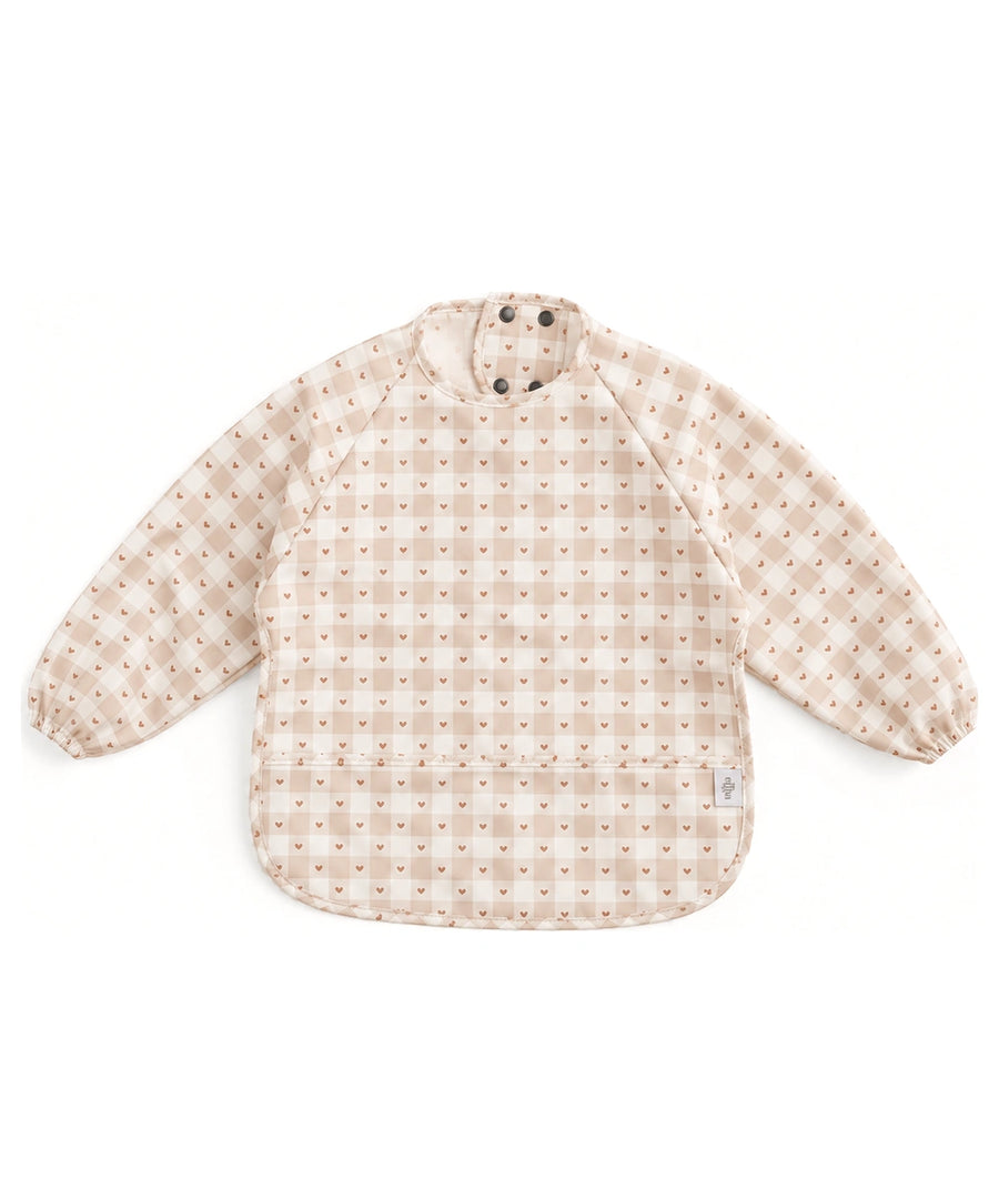 Bavoir tablier à manches longues Jolis carreaux de Mrs Ertha, à carreaux crème et beige et petits cœurs, sur fond blanc