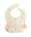 Bavoir en silicone Circus de la marque Mushie sur fond blanc