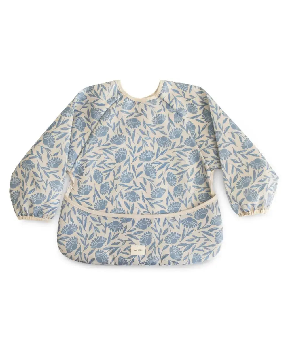 Bavoir tablier Blue Flowers de la marque Mushie sur un fond blanc