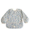 Bavoir tablier Blue Flowers de la marque Mushie sur un fond blanc
