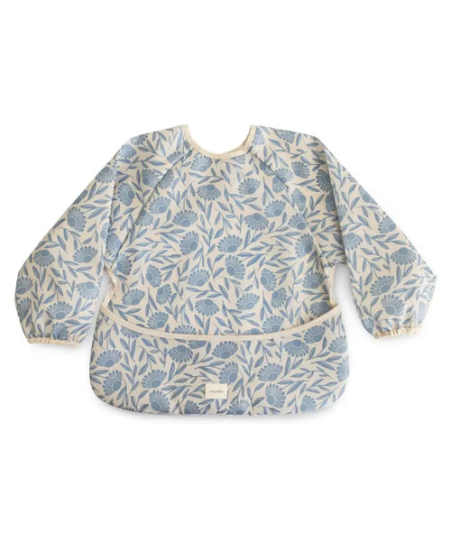 Bavoir tablier Blue Flowers de la marque Mushie sur un fond blanc