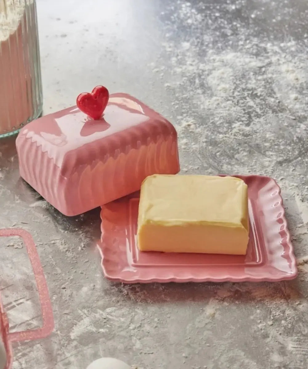 Beurrier en céramique rose et coeur rouge de la marque danoise Rice - posé sur une table