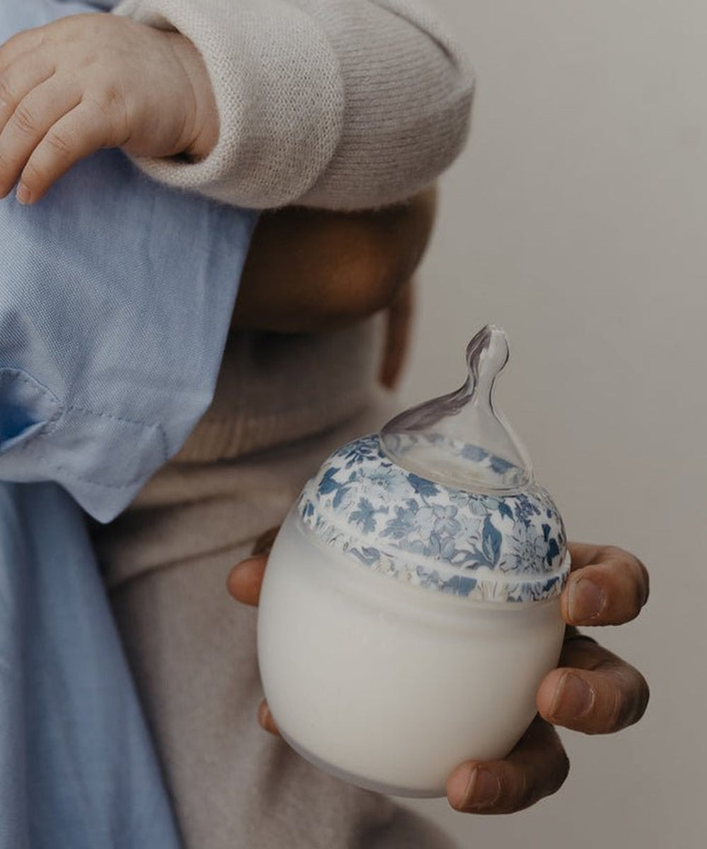 Biberon Élhée Liberty Honey Dew Blue tenu en main pendant un moment avec bébé