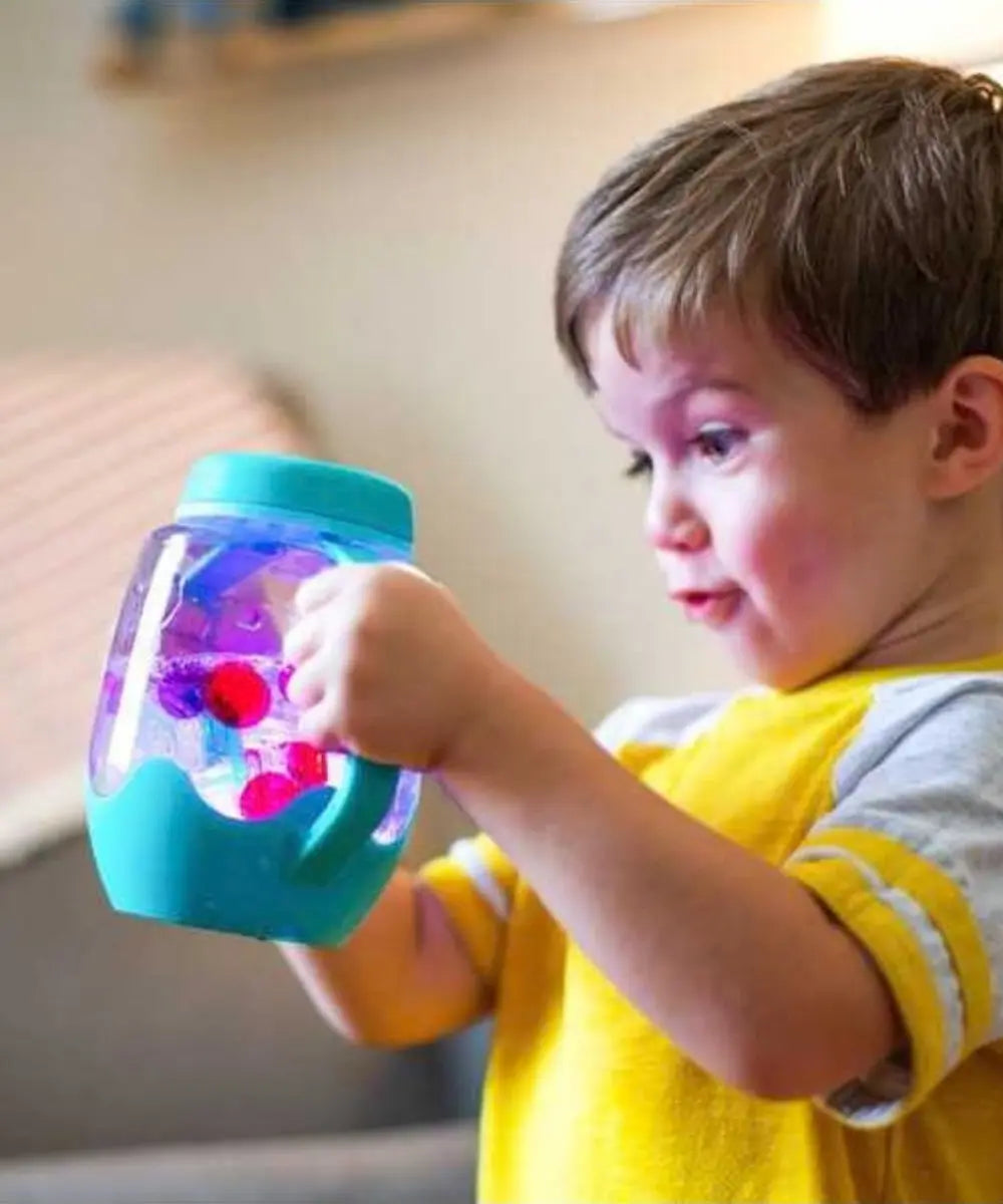 Enfant en train d'admirer le Bocal de jeu sensoriel lumineux bleu Glo Pals personnalisable avec anses