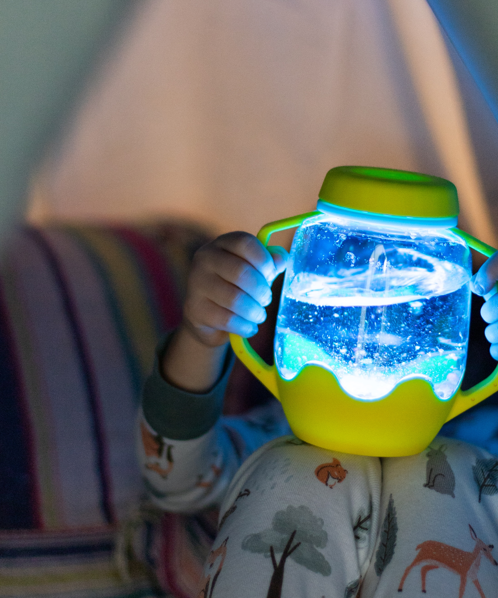 Enfant observant le bocal de jeu sensoriel lumineux jaune Glo Pals