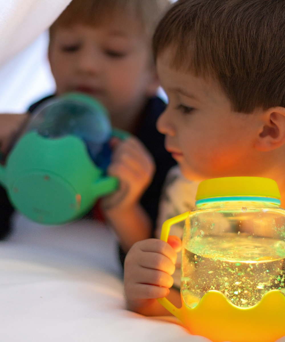 Enfants jouant avec le bocal sensoriel lumineux jaune Glo Pals