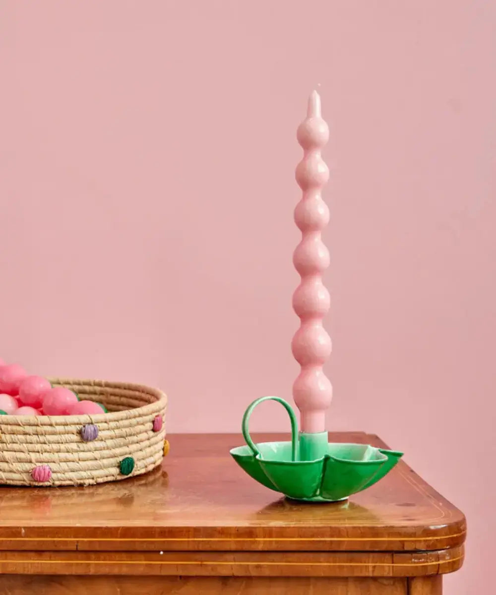 Vue du bougeoir en métal vert posé sur une table en bois avec une chandelle colorée
