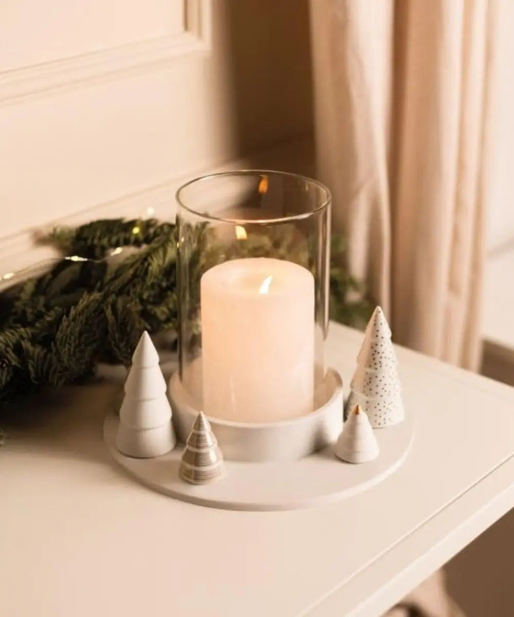 Photophore en porcelaine blanche Räder avec petits sapins sculptes et touches dorées autour du verre.