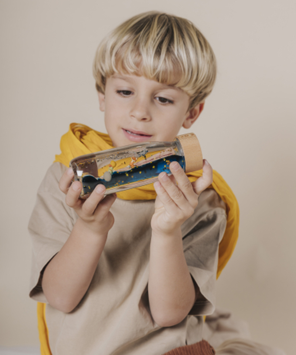 Bouteille sensorielle d'éveil Le Petit Prince avec paillettes et bouchon bois de la marque Petit Boum.