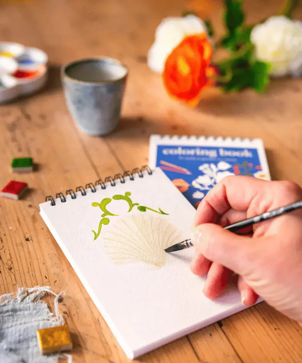 Personne en pleine séance d'aquarelle sur le carnet de coloriage