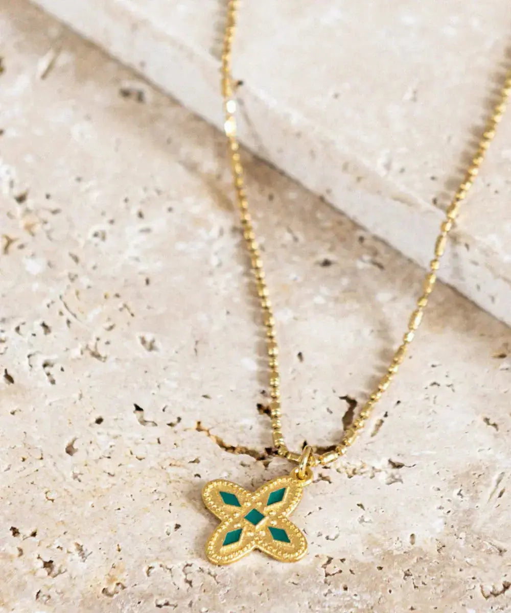 Collier Médaille Adriana Vert Emeraude posée sur une table en marbre