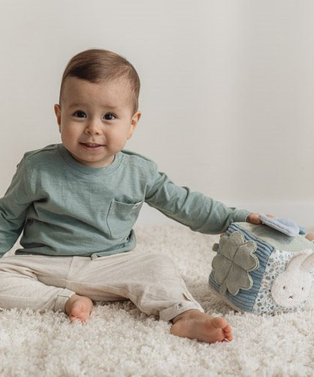 Bébé jouant avec le cube d’activités Miffy sur un tapis