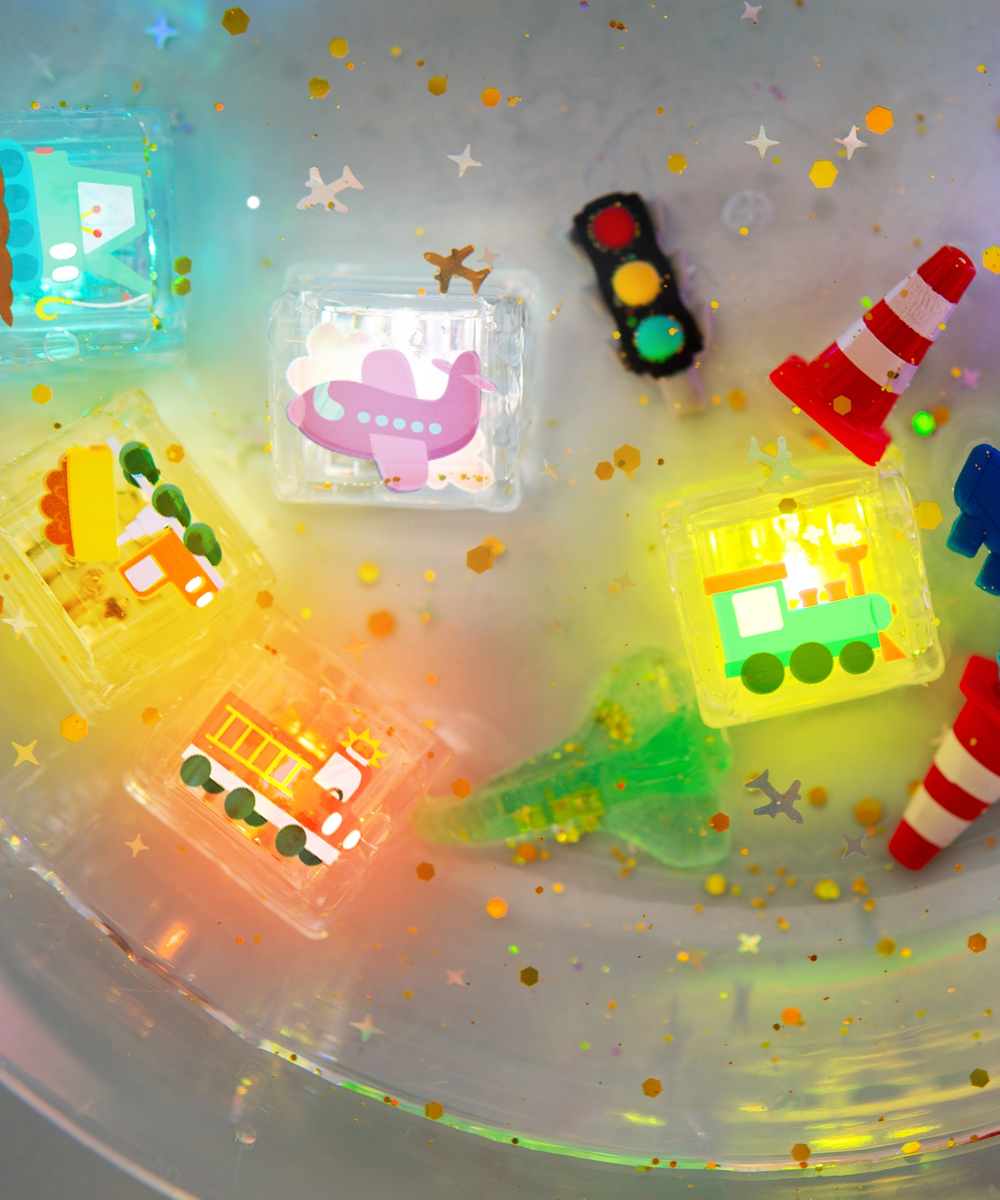 Six véhicules lumineux Glo Pals dans un bac sensoriel