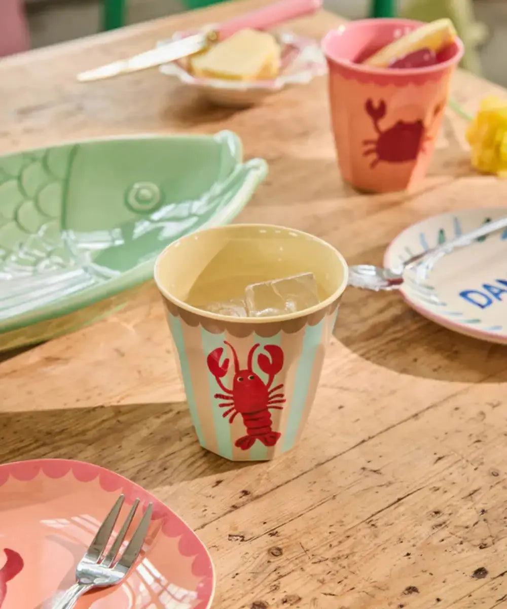 Gobelet en mélamine Homard de Rice posé sur une table colorée
