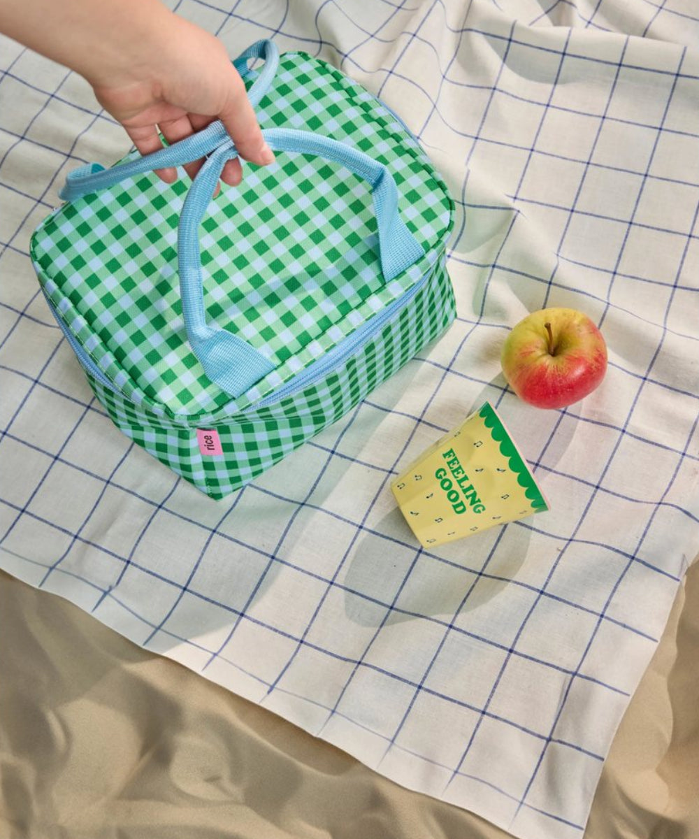 Gobelet en mélamine Snoopy jaune medium posé sur une serviette de plage dans le sable avec un sac isotherme de la marque rice