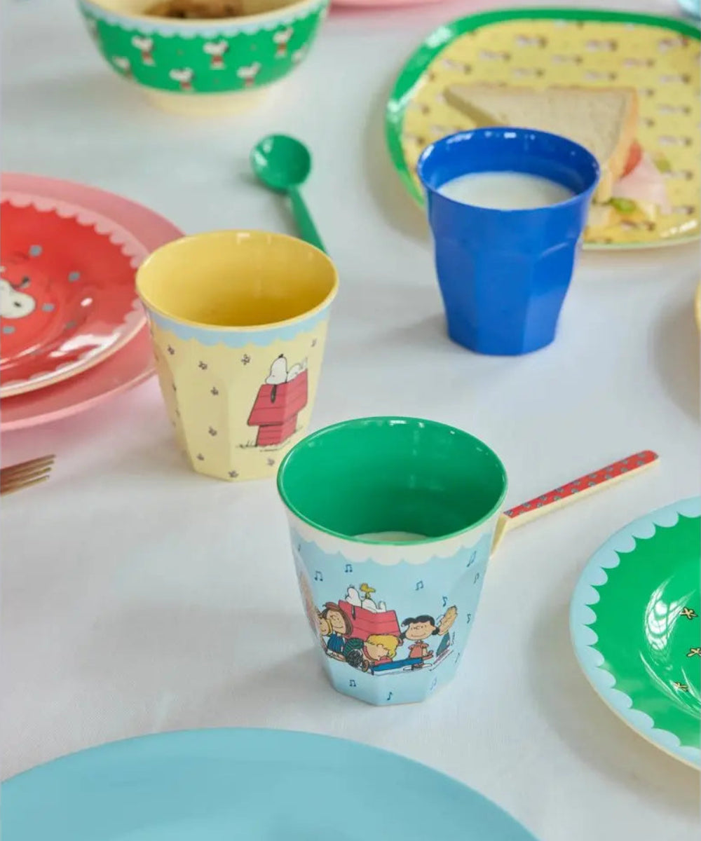 Gobelet en mélamine Snoopy rouge posé sur une table dressée avec des assiettes et des verres de la collection Snoopy