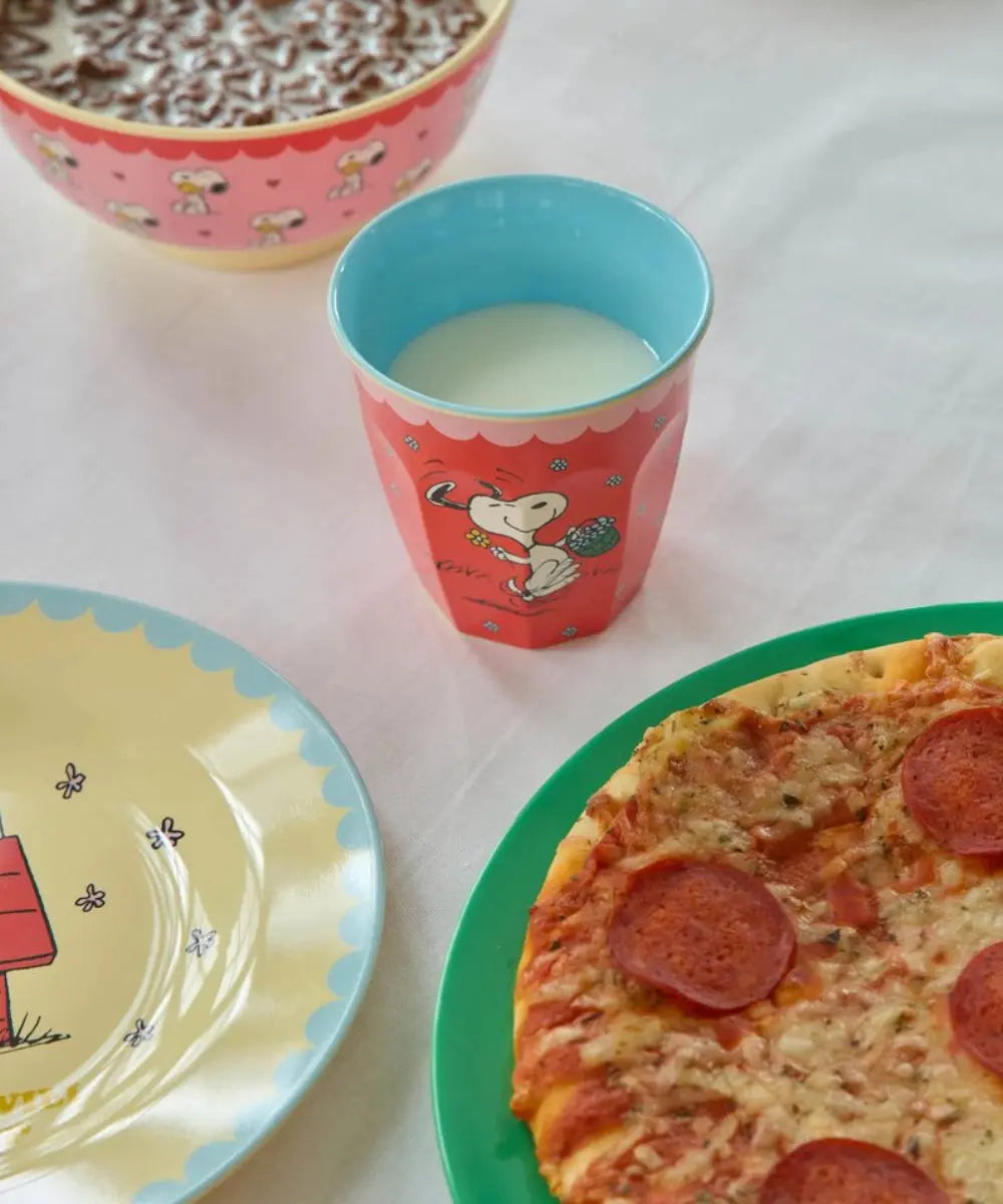 Gobelet en mélamine Snoopy rouge posé sur une table dressée avec un bol et 2 assiettes de la collection Snoopy