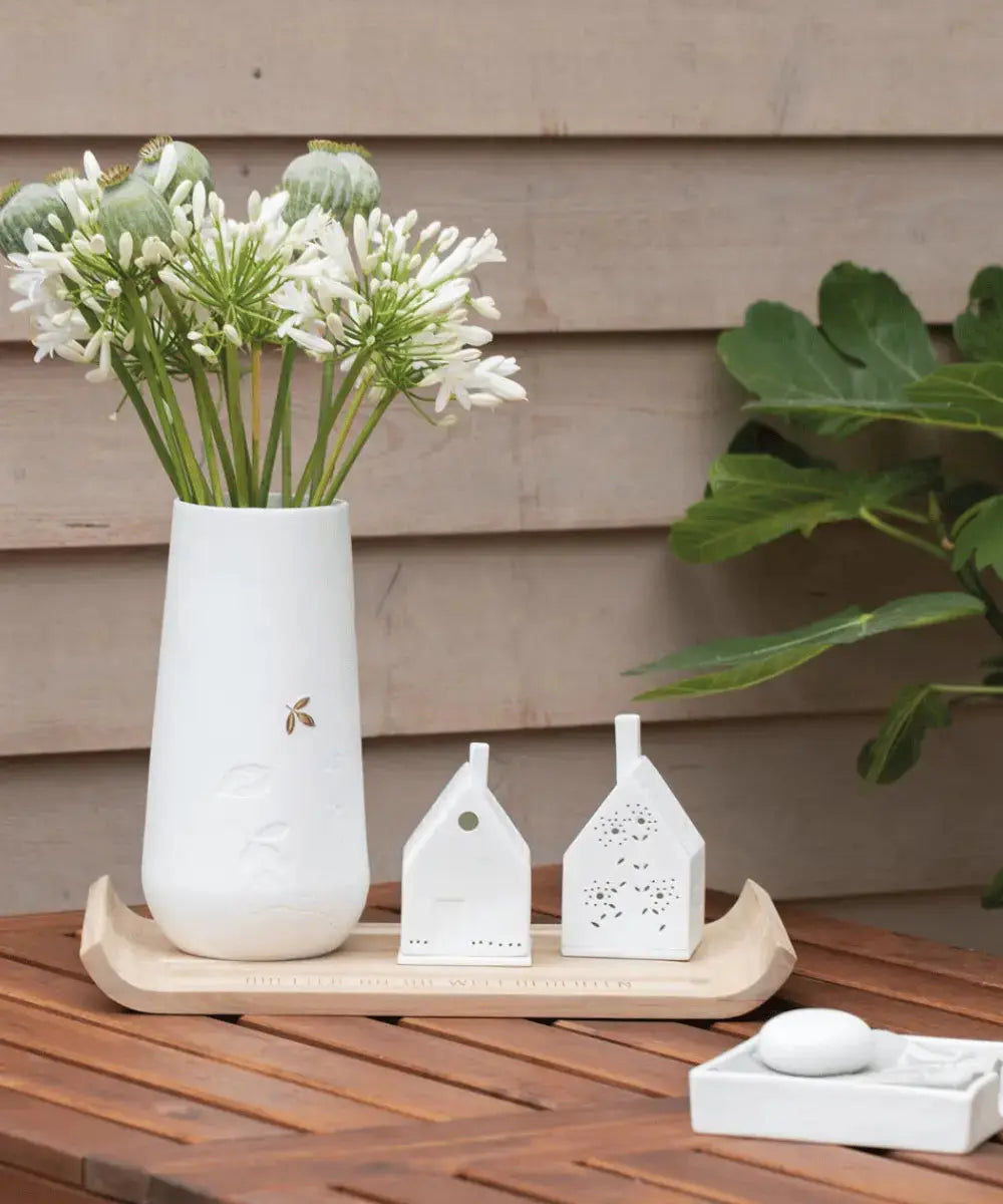 Vase feuilles dorées de Räder avec un bouquet de fleurs blanches dedans
