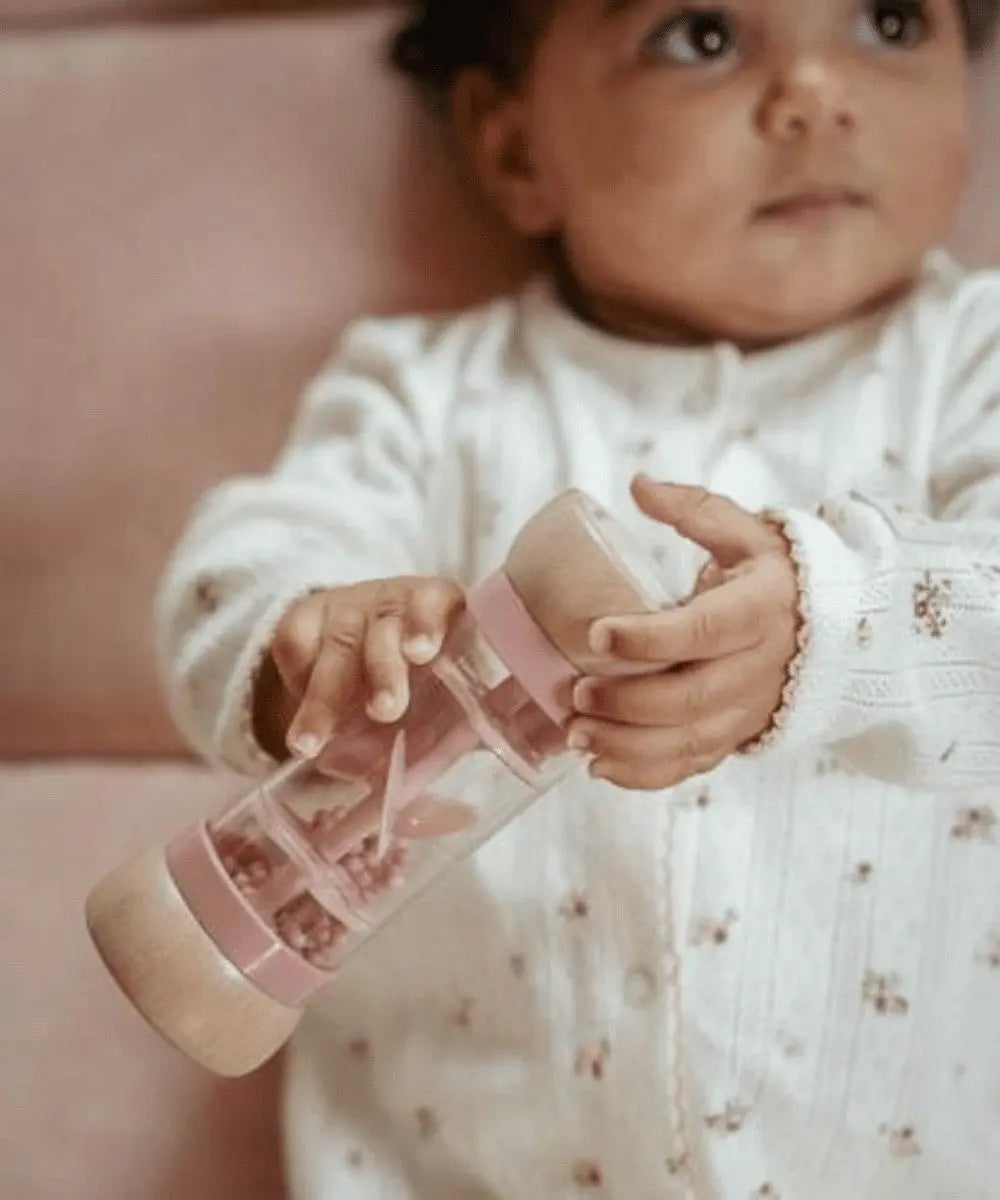 Bébé en train de jouer avec le Hochet de Pluie Rose Fairy Garden de la marque pour enfant Little Dutch
