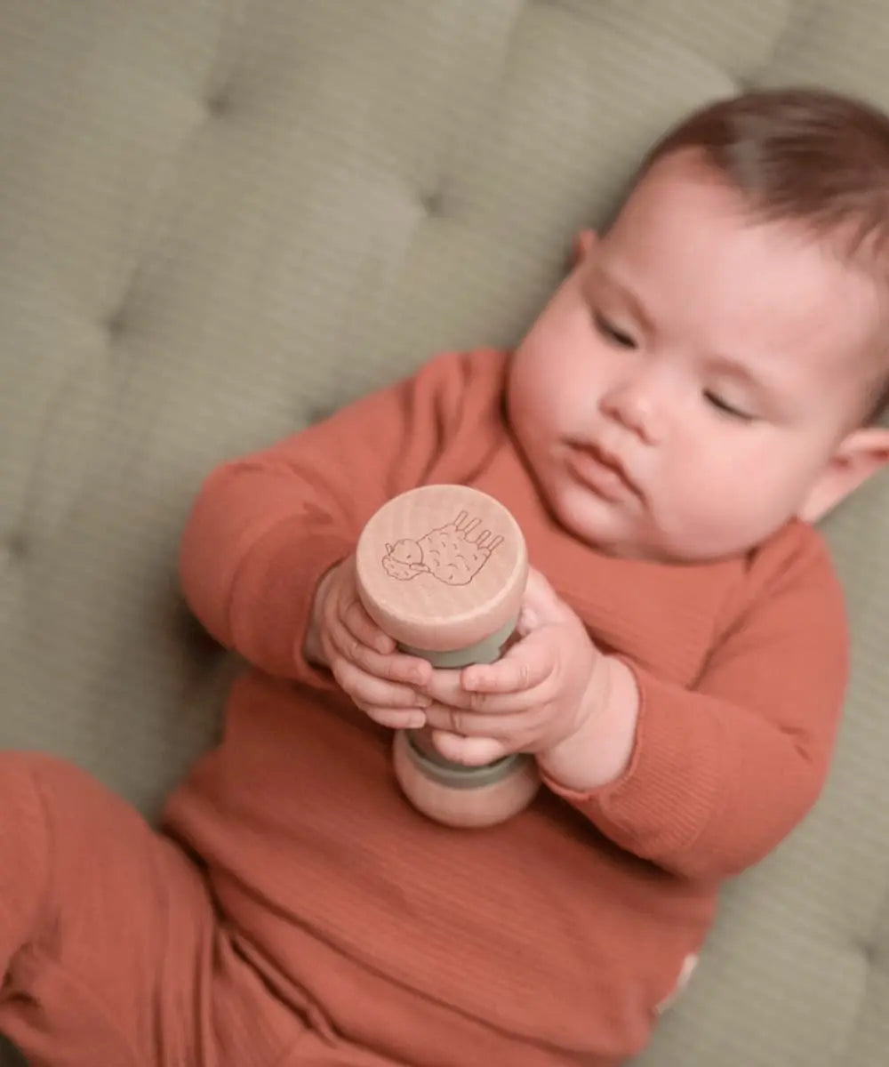 Bébé manipulant le hochet de pluie Little Dutch pour écouter le son de l'eau.