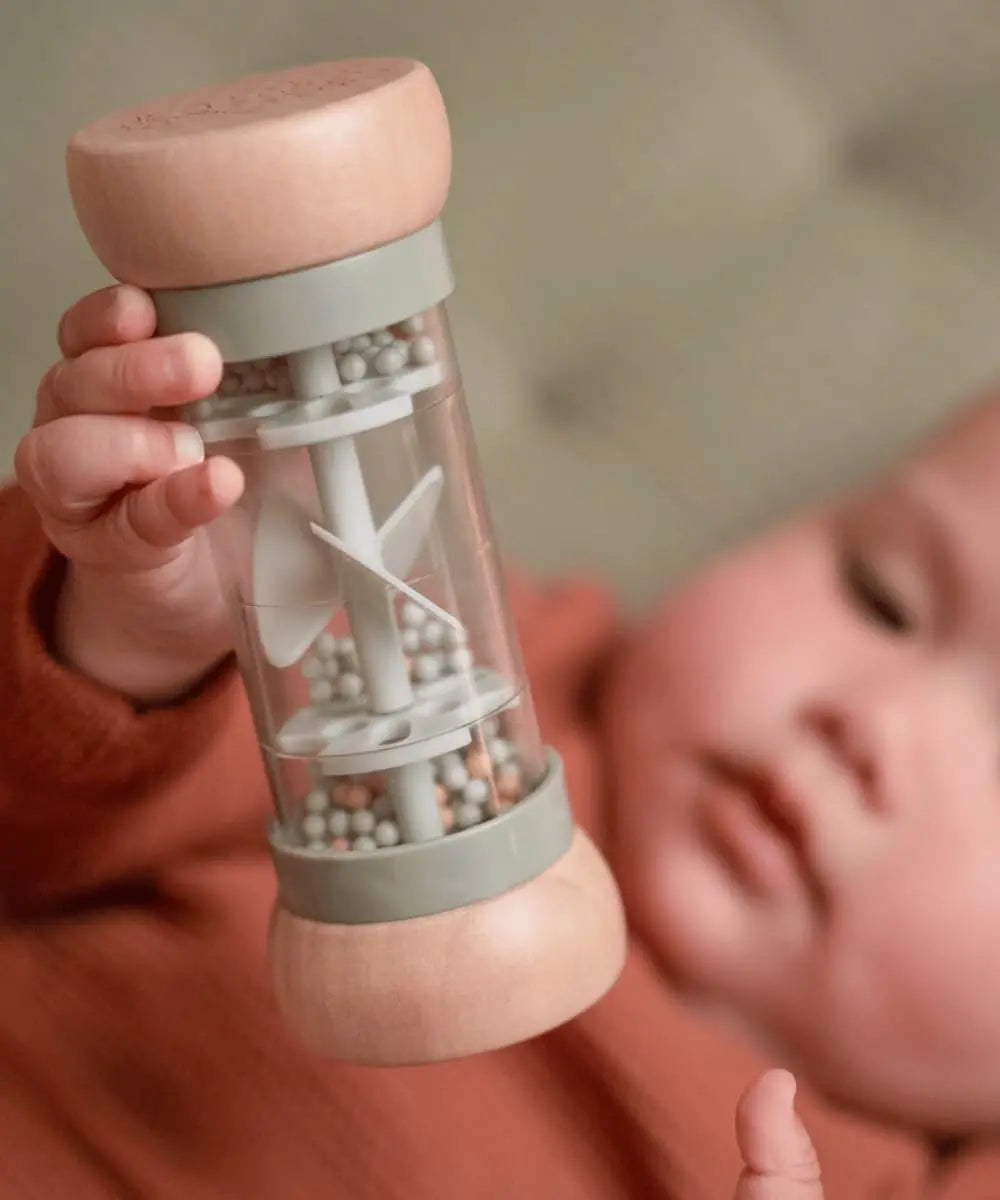 Zoom du hochet de pluie Little Farm dans les mains d'un bébé