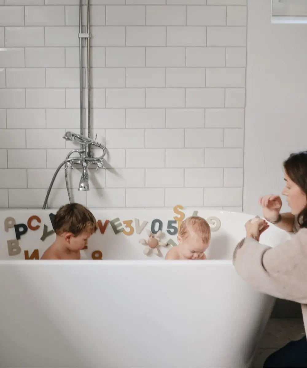 Enfants en train de jouet avec la roue à eau de Mushie dans leur bain
