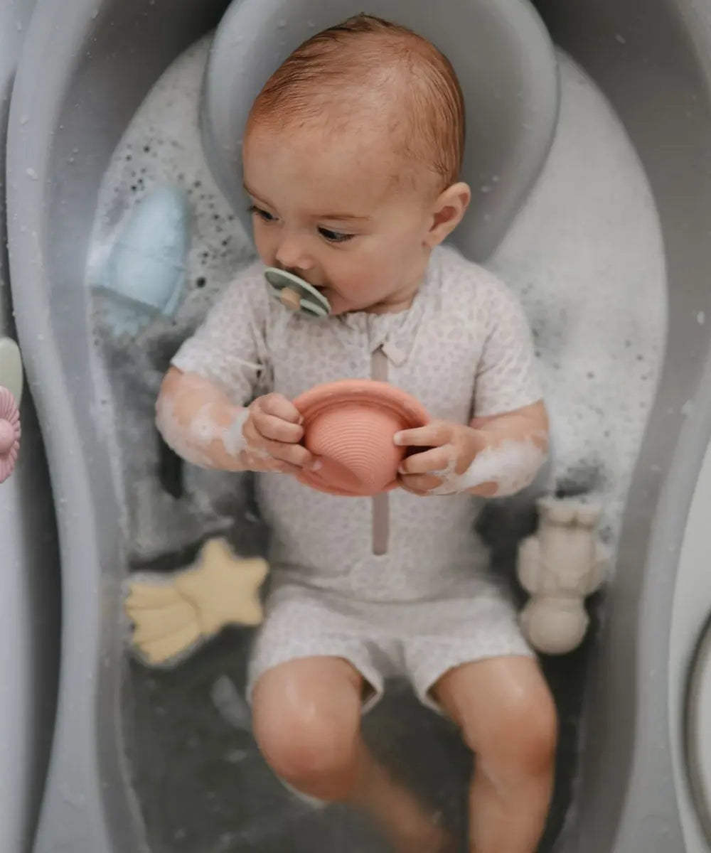 Bébé en train de jouer avec les Jouets pour le bain en silicone Espace de la marque Mushie