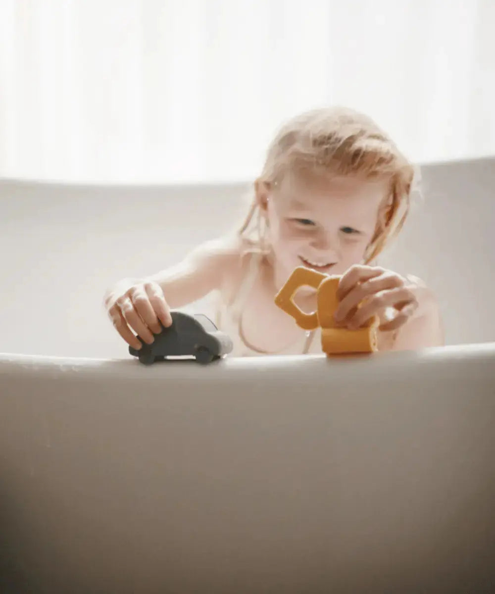 Enfant en train de jouer avec les jouets pour le bain Mushie