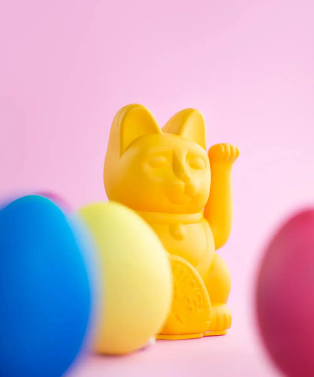 Petit chat porte-bonheur japonais Maneki Neko couleur jaune moutarde mat qui fait signe de la patte.