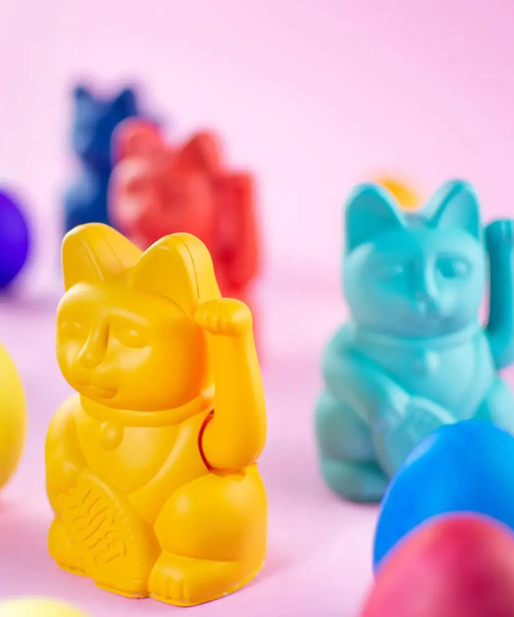 Petit chat porte-bonheur japonais Maneki Neko couleur jaune moutarde mat qui fait signe de la patte.