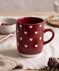 Mug rouge à petits cœurs clairs, présenté sur une table