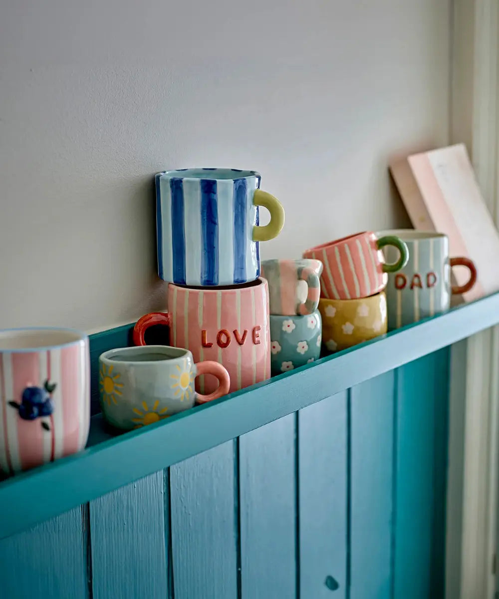 Mug en grès Mom Cherish de la marque de décoration Bloomingville posé sur une étagère