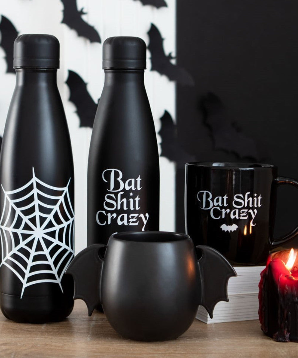 Mug noir ailes de chauve-souris de la marque Something Different, présenté dans une décoration gothique