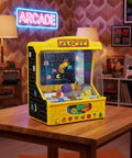 Borne d'arcade Pousse pièces Pac Man posé sur une table dans une pièce rétro