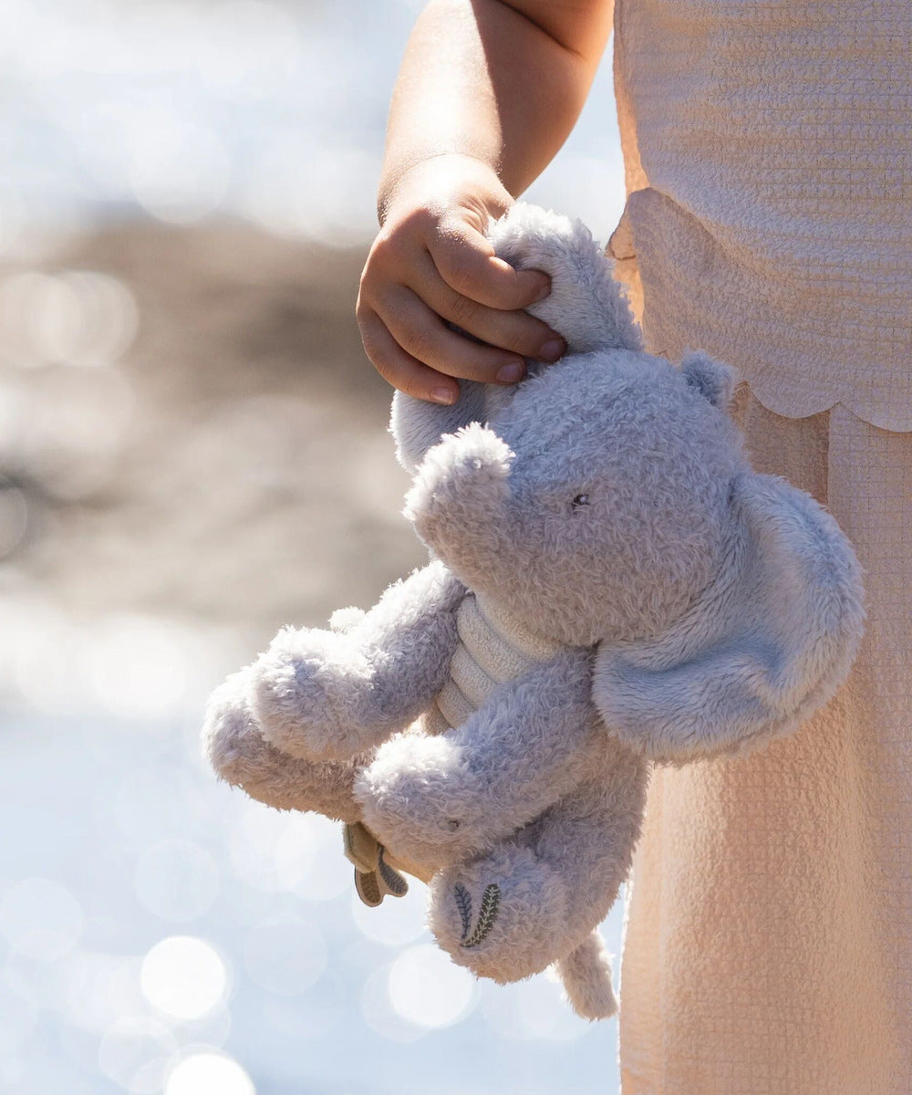 Enfant tenant la peluche éléphant Safari Friends au bord de l’eau